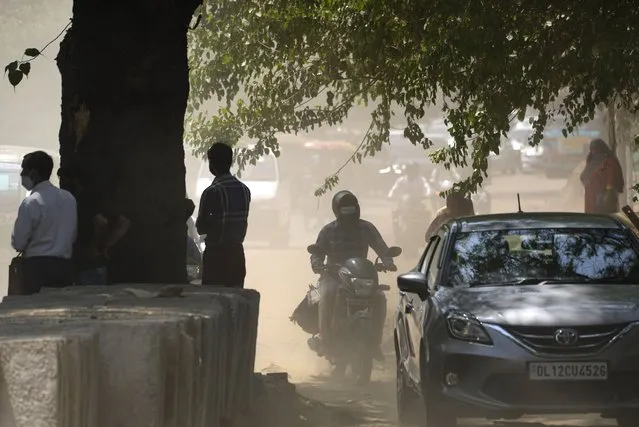 Commuters drive amidst dust and a heat wave that lashes the capital, in New Delhi, India, Monday, April 11, 2022. (Photo by Manish Swarup/AP Photo)