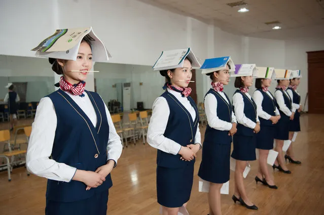 Students training to be flight attendants hold books on their heads, chopsticks in their mouths, and papers in between their knees, as they take part in a standing posture practice at a vocational school in Shijiazhuang, Hebei province, China May 4, 2017. (Photo by Reuters/Stringer)