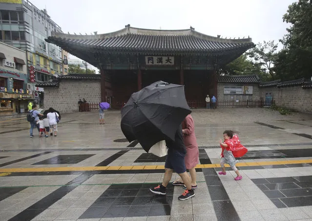 A family braves the strong wind and rain caused by Typhoon Lingling in Seoul, South Korea, Saturday, September 7, 2019. A typhoon passed along South Korea's coast Saturday, toppling trees, grounding planes and causing at least two deaths before the storm system made landfall in North Korea. (Photo by Ahn Young-joon/AP Photo)