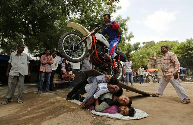 A Hindu devotee performs a stunt with his motorcycle during a rehearsal for the annual Rath Yatra, or chariot procession, in the western Indian city of Ahmedabad June 22, 2014. The annual religious procession commemorates a journey by Hindu god Jagannath, his brother Balabhadra and sister Subhadra, in specially made chariots. The Rath Yatra will be held on June 29. (Photo by Amit Dave/Reuters)