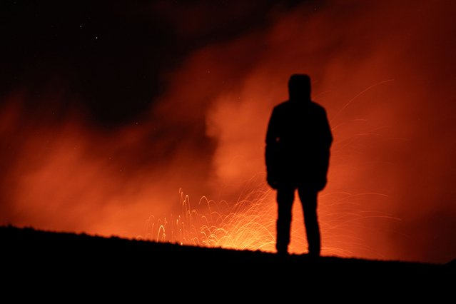 A person looks on as smoke and lava rise from a crater of Mount Etna, Europe's most active volcano in Italy on July 22, 2024. (Photo by Marco Restivo/Etna Walk via Reuters)