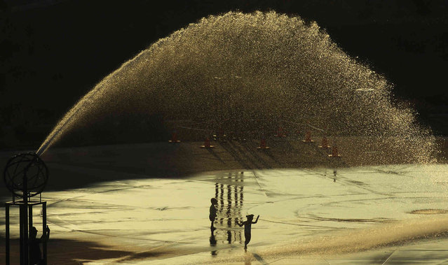 Children run through the Whirlpool Compass Fountain as the sun sets during a heat wave Monday, August 26, 2024, in St. Joseph, Mich. (Photo by Don Campbell/The Herald-Palladium via AP Photo)