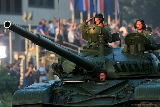 A soldier salutes from a M-84 tank during a military parade in downtown of Zagreb, Croatia, August 4, 2015. (Photo by Antonio Bronic/Reuters)