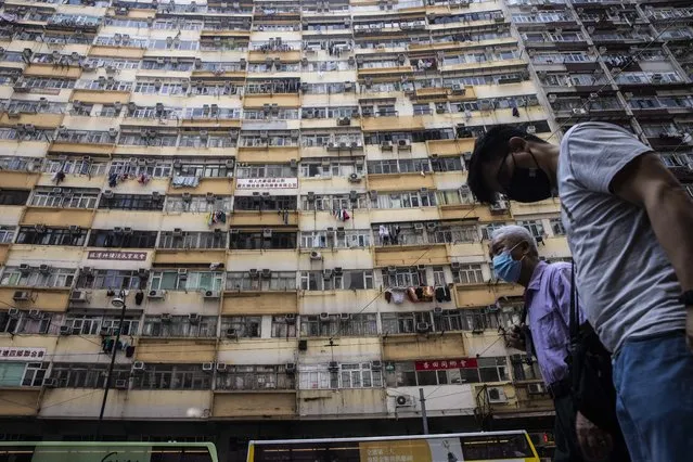 People walk past a residential apartment block in Hong Kong on May 20, 2022. (Photo by Isaac Lawrence/AFP Photo)