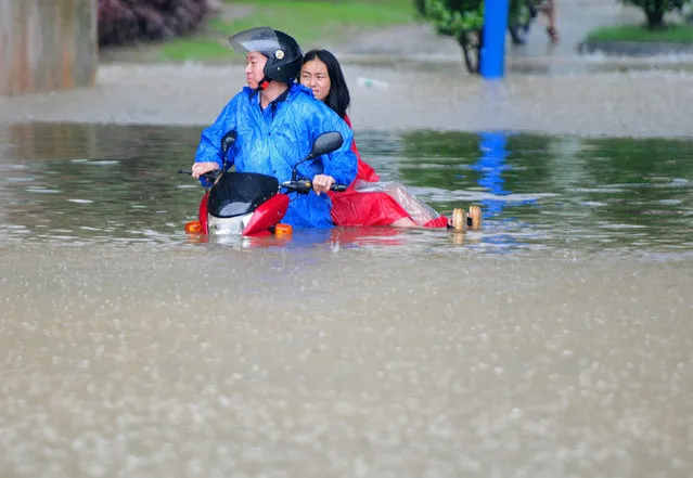 Residents riding a vehicle try to make their way through a flooded area during heavy rainfall in Jiujiang, Jiangxi Province, China, June 19, 2016. (Photo by Reuters/Stringer)