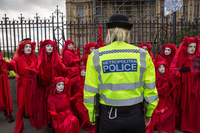 Environmentalist performance art troupe the “Red Rebel Brigade” perform before a police officer, during the environmental protest by Extinction Rebellion activist group in London, UK on October 8, 2019. Extinction Rebellion is an international movement that uses non-violent civil disobedience in an attempt to halt mass extinction and minimise the risk of social collapse. The group has blocked a number of key junctions in central London. (Photo by Rahman Hassani/SOPA Images/Rex Features/Shutterstock)