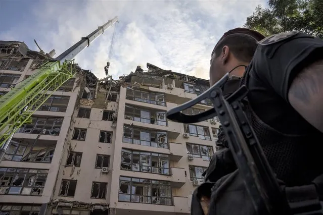 Servicemen work at the scene at a residential building following explosions, in Kyiv, Ukraine, Sunday, June 26, 2022. Several explosions rocked the west of the Ukrainian capital in the early hours of Sunday morning, with at least two residential buildings struck, according to Kyiv mayor Vitali Klitschko. (Photo by Nariman El-Mofty/AP Photo)