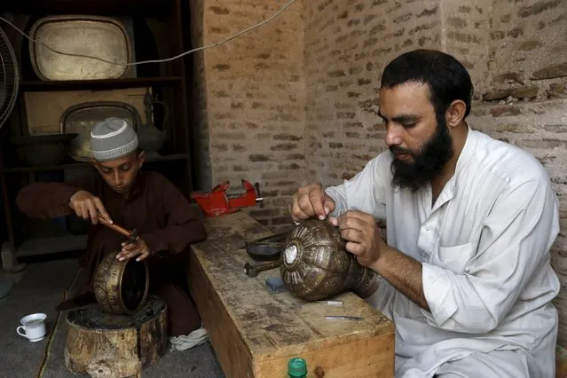An artisan teaches a child the art of engraving on copper utensils under a project initiated by the Tourism Corporation of Khyber Pakhtunkhwa at the Culture Tourist and Artisan Center inside the Gor Khatri Archaeological Complex in Peshawar, Pakistan, August 19, 2015. (Photo by Khuram Parvez/Reuters)