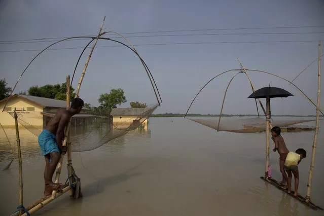 Villagers fish in floodwaters in Morigaon district, east of Gauhati, northeastern state of Assam, Tuesday, August 15, 2017. Deadly landslides and flooding are common across South Asia during the summer monsoon season that stretches from June to September. (Photo by Anupam Nath/AP Photo)