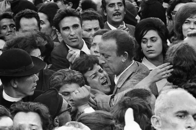 A man tries to calm a woman in summer heat and the crushing crowds in St. Peter's Square, June 6, 1963, shortly before Pope John XXIII's body was carried out so the public night pay a final tribute. (Photo by AP Photo)