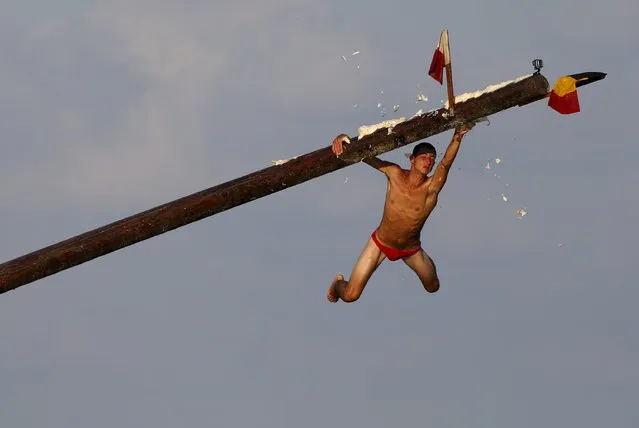 A competitor slips off the “gostra”, a pole covered in grease, during the celebrations for the religious feast of St Julian, patron of the town of St Julian's, outside Valletta August 30, 2015. (Photo by Darrin Zammit Lupi/Reuters)