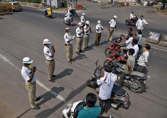 Members of traffic police fold their hands as they request the commuter to wear masks and to stay at home during a 21-day nationwide lockdown to limit the spreading of coronavirus disease (COVID-19), in Vijayawada in the southern state of Andhra Pradesh, India, March 27, 2020. (Photo by Idrees Mohammed/Reuters)