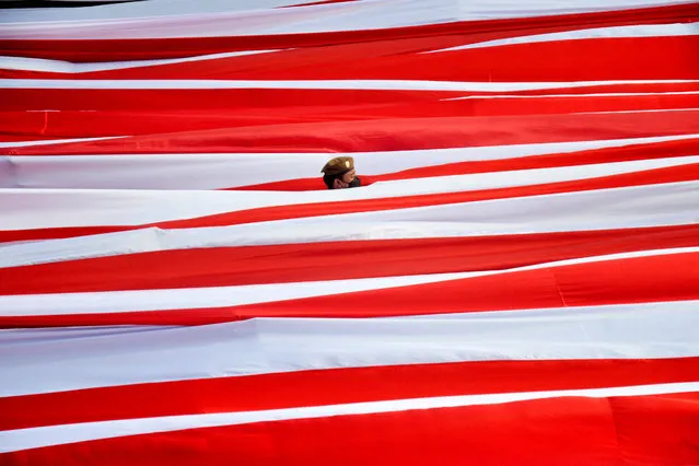 A municipal officer stands among the national flag during celebrating Indonesia's 77th Independence Day at Losari Beach, Makassar, South Sulawesi province, Indonesia on August 17, 2022, in this photo taken by Antara Foto. (Photo by Abriawan Abhe/Antara Foto via Reuters)