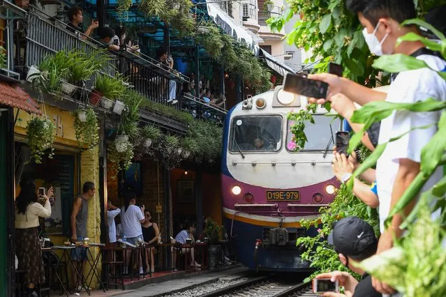 Tourists take photos of a train passing through an old residential area in central Hanoi on August 28, 2022. (Photo by Nhac Nguyen/AFP Photo)