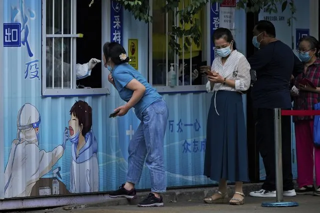 Residents get their routine COVID-19 throat swabs at a coronavirus testing site along a street in Beijing, Monday, August 29, 2022. (Photo by Andy Wong/AP Photo)
