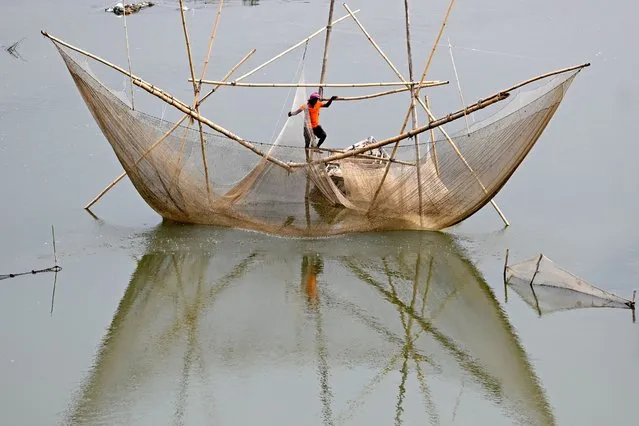 A fisherman stands on a fishing net in the waters of river Yamuna in New Delhi on September 6, 2022. (Photo by Sajjad Hussain/AFP Photo)