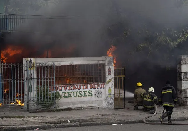 Firefighters try to extinguish a fire set by demonstrators during a protest in Port-au-Prince, Haiti, Monday, August 22, 2022. (Photo by Odelyn Joseph/AP Photo)