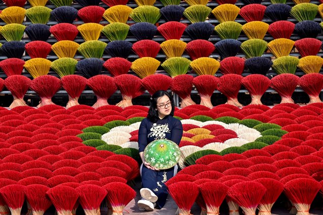 A tourist poses in front of incense sticks drying in a courtyard in Quang Phu Cau village on the outskirts of Hanoi on January 21, 2025, ahead of Lunar New Year celebrations, known in Vietnam as Tet. (Photo by Nhac Nguyen/AFP Photo)