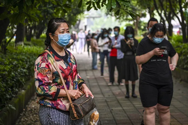 Wuhan residents wearing face masks wait in a line to be tested of COVID-19 in a neighborhood in Wuhan, in Chinas central Hubei province on May 15, 2020. China has largely brought the virus under control, but the emergence of new cases in Wuhan in recent days, after weeks without fresh infections, has prompted a campaign to test all 11 million residents in the city where COVID-19 first emerged late last year. (Photo by Hector Retamal/AFP Photo)