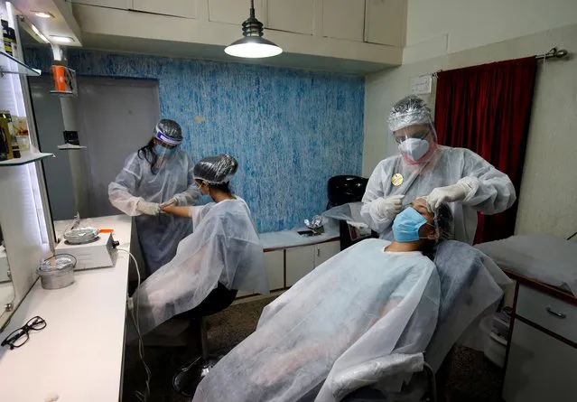 Beauticians wearing protective gears tend to their customers inside a parlor after authorities allowed saloons and beauty parlors to open, during an extended nationwide lockdown to slow the spreading of the coronavirus disease (COVID-19), in Ahmedabad, India, May 19, 2020. (Photo by Amit Dave/Reuters)