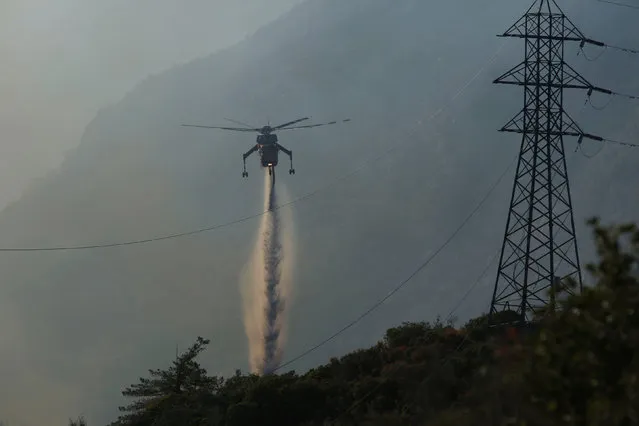 A firefighting helicopter makes a water drop near power lines during the Pilot Fire in San Bernardino county near the Deer Lodge Park area in Lake Arrowhead, California, U.S. August 9, 2016. (Photo by Patrick T. Fallon/Reuters)