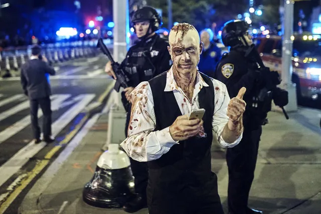 A reveler gets his picture taken by a friend in front of heavily armed police during the Greenwich Village Halloween Parade, Tuesday, October 31, 2017, in New York. (Photo by Andres Kudacki/AP Photo)