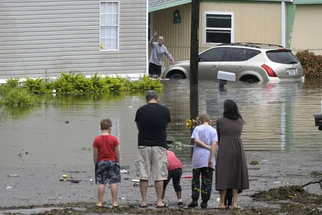 Residents check on one another in a flooded neighborhood in the aftermath of Hurricane Ian, Thursday, September 29, 2022, in Orlando, Fla. (Photo by Phelan M. Ebenhack/AP Photo)