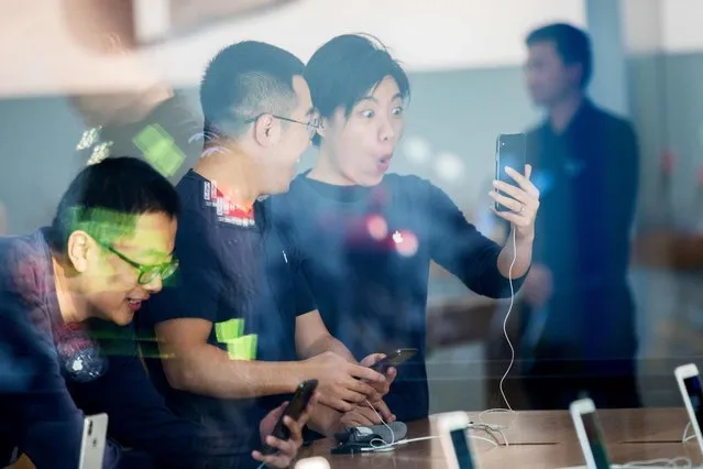 Chinese customers look at the new iPhone X at the Apple store in Hangzhou in China's eastern Zhejiang province on November 3, 2017. Apple profits soared by a fifth as its flagship iPhone X hit stores in Asia on November 3, with the company predicting bumper sales despite its eye-watering price tag. (Photo by AFP Photo/Stringer)