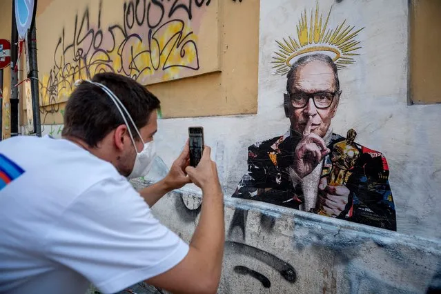 A man takes a picture of the mural painted by the street artist Harry Greb depicting the Italian music composer Ennio Morricone, a day after the 91-year-old composer's death, on July 7, 2020 in Rome, Italy. (Photo by Antonio Masiello/Getty Images)