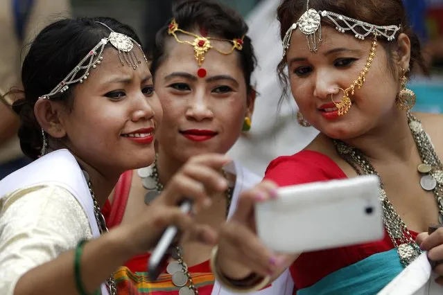 Nepalese women in traditional attires take their selfie as they participate in a rally to mark World Indigenous Day in Kathmandu, Nepal, Tuesday, August 9, 2016. According to a 2011 census, the indigenous nationalities of Nepal constitute over 30% of the total population and includes over 60 different groups. (Photo by Niranjan Shrestha/AP Photo)