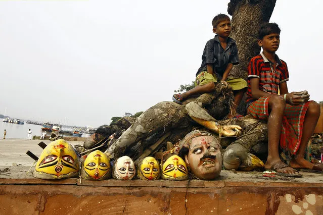 Boys sit next to clay idols of the Hindu goddesses and a demon after idols of Durga were immersed into the Ganges river in Kolkata October 3, 2014. (Photo by Rupak De Chowdhuri/Reuters)