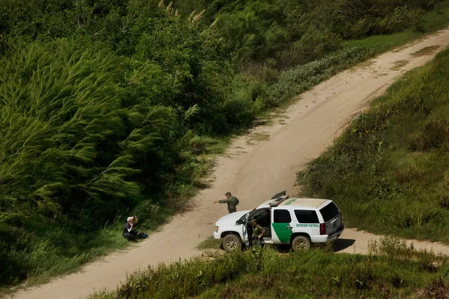 A migrant surrenders to border patrol on the banks of the Rio Grande river. This man was waving to the helicopters and waiting to be picked up by border patrol. Self-presenting became common in 2014 with asylum seekers from Central America fleeing violence and poverty. (Photo by Kirsten Luce/Getty Images)