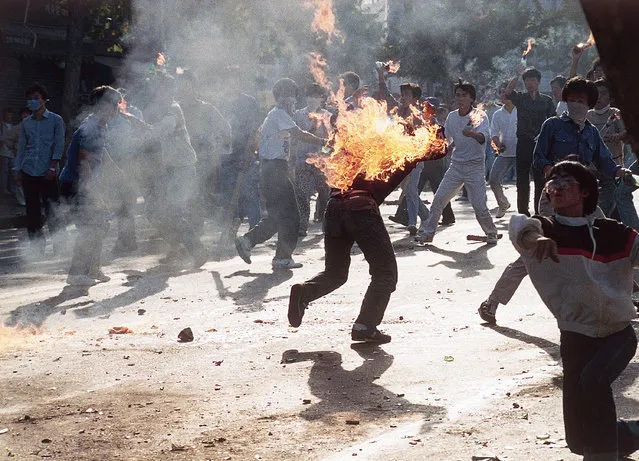 A South Korean student engulfed in flames runs for safety as his compatriots launch home-made firebombs toward riot police during anti-government, anti-Olympic demonstrations at Korea University in Seoul, South Korea on September 29, 1988. (Photo by AP Photo)