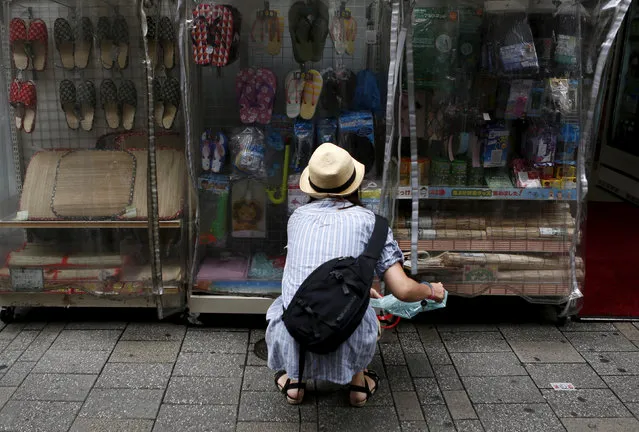 A shopper looks at items outside a discount store at a shopping district in Tokyo, June 18, 2015. (Photo by Yuya Shino/Reuters)