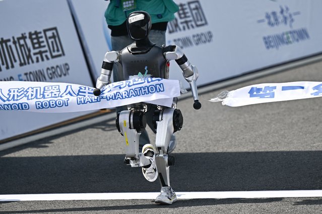 A robot crosses the finish line in the humanoid robot half marathon in Beijing on April 19, 2025. Dozens of humanoid robots took to the streets of Beijing, joining thousands of their flesh-and-blood counterparts in a world-first half marathon showcasing China's drive to lead the global race in cutting-edge technology. (Photo by Pedro Pardo/AFP Photo)