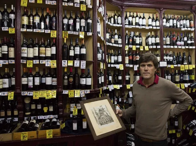 Alberto Moran, manager of liquor store Mariano Madrueno just off Gran Via, one of Madrid's main arteries, poses with an old photo at his shop October 23, 2014. Spain's independent retailers remain enmeshed in the fabric of daily life at a time when chains and multinationals dominate in much of the rest of western Europe. (Photo by Sergio Perez/Reuters)