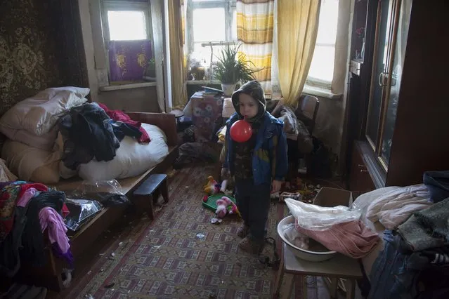 In this photo taken on Tuesday, October 28, 2014, 5-year-old Maxim stands in a room of his damaged house  in the Petrovsky district in the town of Donetsk, eastern Ukraine. (Photo by Dmitry Lovetsky/AP Photo)