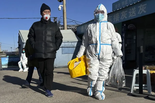 Family members in protective gear collect the cremated remains of their loved one bundled with yellow cloth at a crematorium in Beijing, Saturday, December 17, 2022. (Photo by Ng Han Guan/AP Photo)