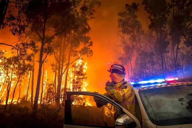 This handout photo taken on January 14, 2018 by DFES incident photographer Evan Collis and released to AFP on January 15, 2018 by the Department of Fire and Emergency Services (DFES) of Western Australia shows a firefighter monitoring a bushfire in the eastern suburbs of Perth. Smoke from the fires has spread across the city of Perth, dropping ash in many nearby neighbourhoods. (Photo by Evan Collis/AFP Photo/Department of Fire and Emergency Services of Western Australia)