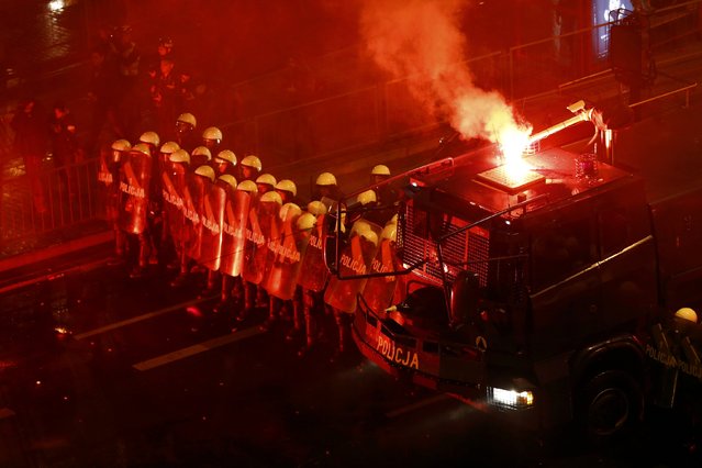 Riot policemen stand next to a water cannon as several hundred masked men who broke away from a far-right march threw stones and flares in Warsaw November 11, 2014. Nationalist groups march through Warsaw each year to mark the anniversary of Polish independence, but for the fourth year in a row the procession turned violent. (Photo by Kacper Pempel/Reuters)