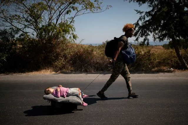 A migrant pulls a girl lying on a cart, following a fire at the Moria camp on the island of Lesbos, Greece, September 11, 2020. (Photo by Alkis Konstantinidis/Reuters)