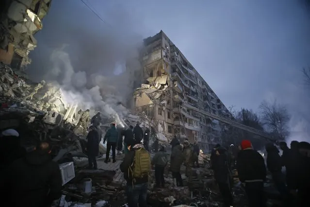 Emergency workers clear the rubble after a Russian rocket hit a multistory building leaving many people under debris in Dnipro, Ukraine, Saturday, January 14, 2023. (Photo by Roman Chop/AP Photo)