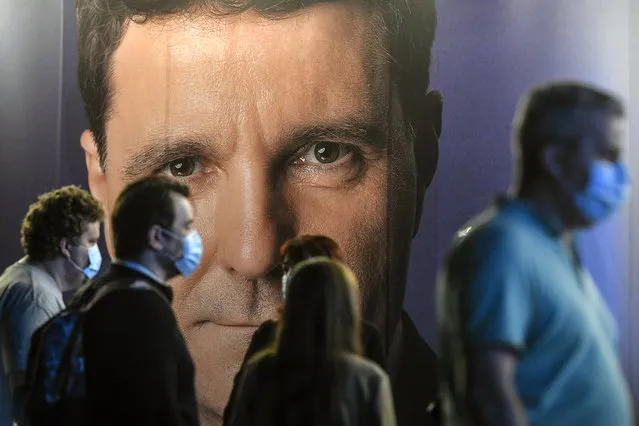 People wearing masks for protection against COVID-19 are backdropped by a large poster of Nicusor Dan, candidate for mayor in Bucharest, Romania, Sunday, September 27, 2020. Exit polls place Nicusor Dan, the mayor candidate backed by the USR-PLUS Alliance and the ruling Liberal Party, ahead of the incumbent mayor of the Romanian capital, Gabriela Firea, backed by the Social Democratic Party in local elections. (Photo by Andreea Alexandru/AP Photo)