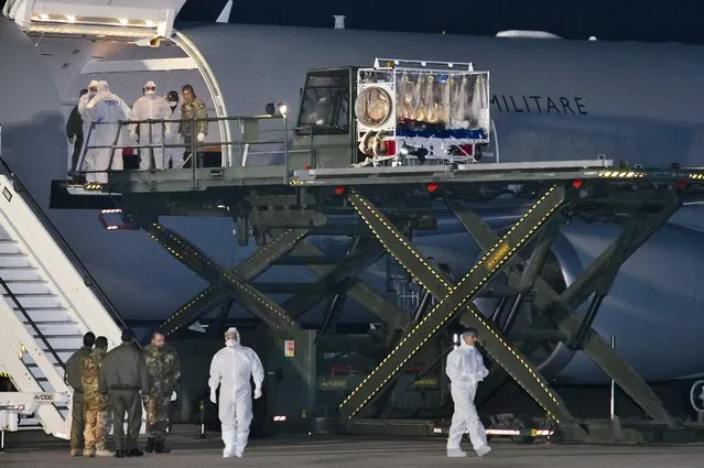 In this photo provided by the Italian Air Force, a KC 767 plane is parked on the tarmac as personnel in biohazard suits disembark a doctor lying in a plastic sealed stretcher, top right, who has tested positive for the Ebola virus, at the Pratica di Mare military airport near Rome, Tuesday, November 25, 2014. (Photo by AP Photo/Italian Air Force)