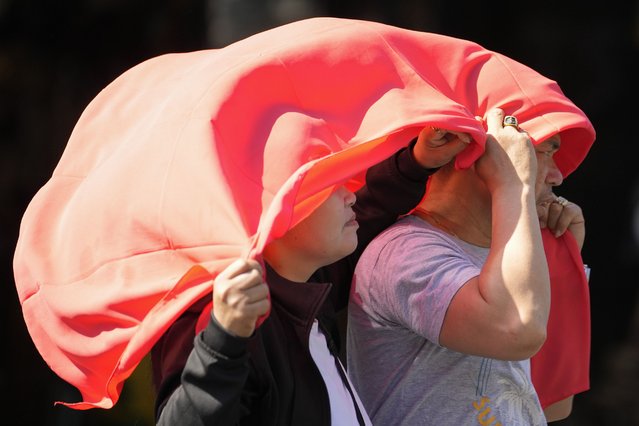 A man and woman use a cloth over their heads to protect them from the sun in Manila, Philippines on Monday, April 29, 2024. (Photo by Aaron Favila/AP Photo)