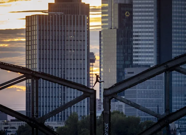 A parkour runner jumps on a railway bridge with the buildings of the banking district in background in Frankfurt, Germany, Wednesday, September 9, 2020. (Photo by Michael Probst/AP Photo)