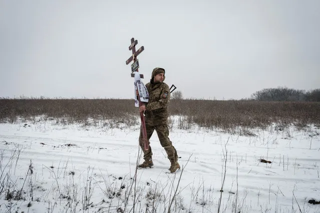 Oleksiy Storozh, 28, carries a cross to be placed at the grave of his late best friend, Ukrainian serviceman of the Azov battalion killed in action in Bakhmut, 28-year-old orphan Oleksandr Korovniy, during a funeral procession at a cemetery in Sloviansk on January 30, 2023, amid the Russian invasion of Ukraine. (Photo by Yasuyoshi Chiba/AFP Photo)