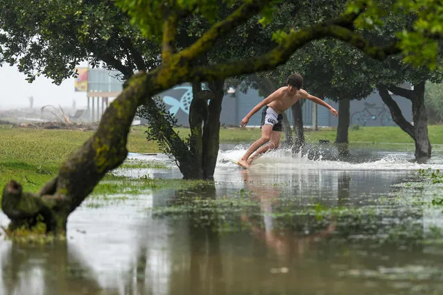 A photo taken on February 14, 2023 shows a boy skimming on floodwaters along Marine Parade in the North Island city of Napier. New Zealand declared a national state of emergency on February 14 as Cyclone Gabrielle swept away roads, inundated homes and left more than 100,000 people without power. (Photo by AFP Photo/Stringer)