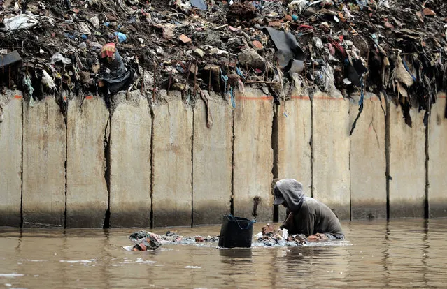 A man grops the riverbed as he searches for valuable goods to resale in Jakarta, on October 13, 2016. Indonesia's public debt to gross domestic product (GDP) ratio stood at 33.05 percent at the end of 2015, according to the World Bank. (Photo by Bay Ismoyo/AFP Photo)