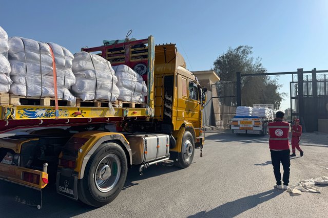 Members of the Egyptian Red Cross look on as trucks loaded with humanitarian aid cross the Rafah border gate, between Egypt and the Gaza Strip, in Rafah, Egypt, 27 July 2025. The Israeli army declared a 'tactical pause' in military operations in parts of the Gaza Strip on 27 July, to facilitate the safe passage of humanitarian aid convoys. (Photo by EPA/EFE/Stringer)